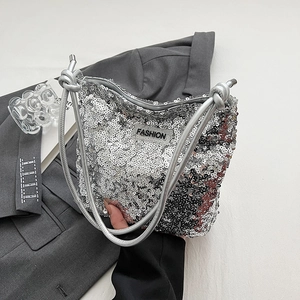 Sac à bandoulière argenté à paillettes avec étiquette FASHION sur costume gris