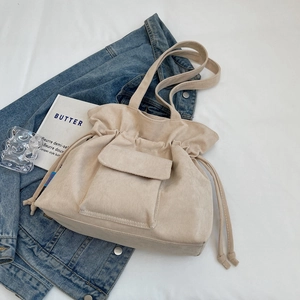 Minimalist beige corduroy bucket bag with drawstring and front flap pocket detail