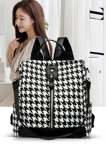 Detailed view of black and white houndstooth backpack with leather trim and front zip
