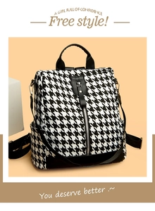 Detailed view of houndstooth backpack with black leather trim and vertical front zipper