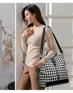 Detail view of stylish houndstooth backpack with black leather trim and nylon straps