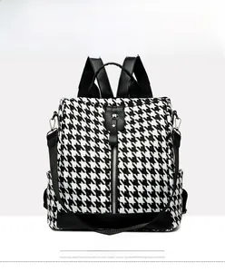 Front detail of houndstooth backpack with black leather straps and metal zippers