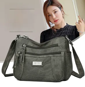 Detailed view of dark army green crossbody bag with multiple functional zip pockets