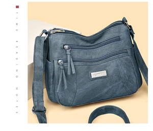 Detail view of denim texture crossbody bag with triple front zippers and adjustable strap