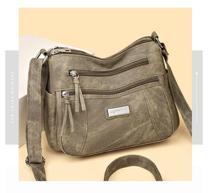 Detail of vintage soft leather crossbody bag with multiple zipper pockets and adjustable strap