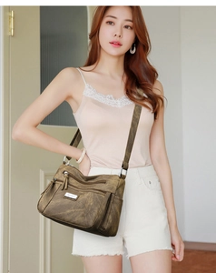 Close-up of retro olive brown crossbody bag showing multiple zip pockets and soft leather texture