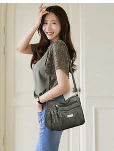Detail of dark grey-green soft leather bag with multi-zipper pockets and adjustable strap