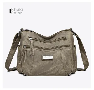 Front detail of khaki soft leather crossbody bag with multiple zippers and tassels