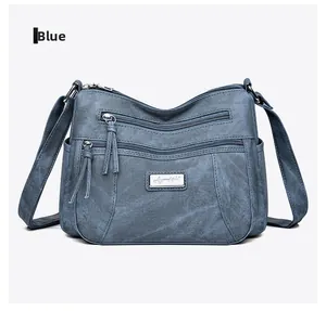 Detail view of blue multi-pocket crossbody bag with soft washed canvas texture and zippers