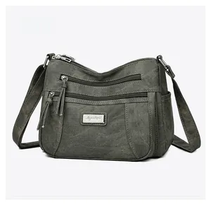 Detail of multi-pocket vintage canvas shoulder bag with metallic logo and sturdy zippers