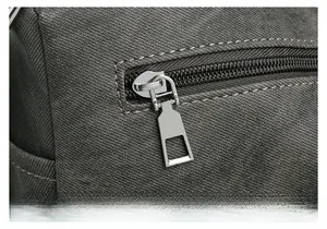 Close-up of smooth silver metal zipper and cross-grain texture on gray crossbody bag