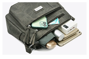Detail of multi-compartment army green canvas crossbody bag showing large storage capacity