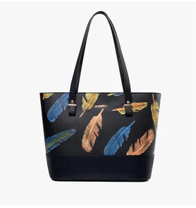 Detail view of black pebble leather tote bag with colorful feather print and gold logo