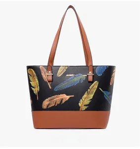 Close-up of black tote bag with feather print and brown textured faux leather base
