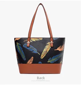Back view of black pebble leather tote bag with vibrant feather print and brown handles