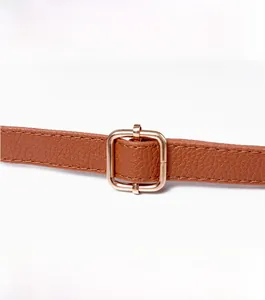 Close-up of adjustable brown pebbled leather shoulder strap with golden metal buckle
