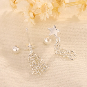 Détail macro de boucles d'oreilles étoile argentées avec poinçon S925 sur tissu
