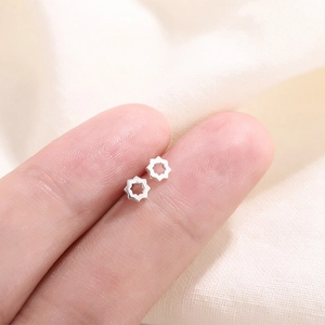 Mini boucles d'oreilles géométriques en argent présentées sur le bout du doigt pour la taille