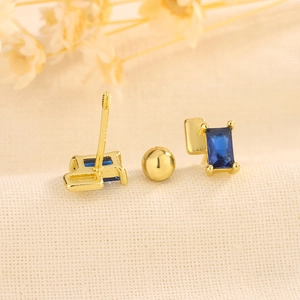 Macro detail of geometric gold earrings with blue zircon and secure screw back design