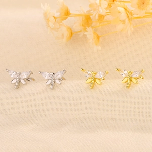 Detailed view of dragonfly earrings with gold and silver finishes and crystal wings
