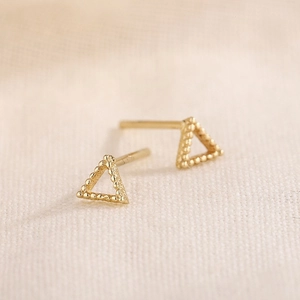Gros plan de boucles d'oreilles triangles dorées avec texture perlée sur tissu