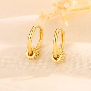 Elegant gold-plated hoop earrings with micro-pave crystal cylinder charms on linen