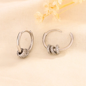 Elegant silver hoop earrings with shimmering crystal-paved beads on a woven surface