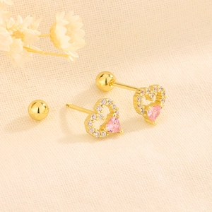 Nahaufnahme von goldenen Herzohrringen mit Zirkonia und rosa Herzsteinen