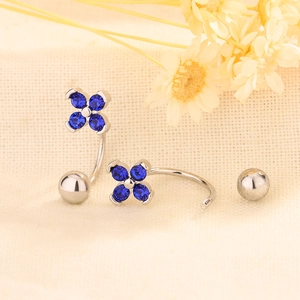 Crochets d'oreilles trèfle en argent avec zircons bleu foncé sur tissu en lin