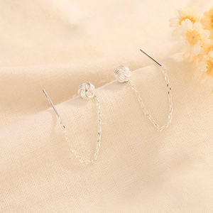 Silver knot tassel earrings in S925 sterling silver dangling on beige linen fabric