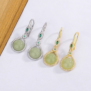 Detailed view of silver and gold teardrop earrings with green jadeite and sparkling zircons