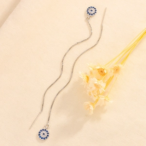 Detailed close-up of Evil Eye threader earrings with blue crystals on canvas background