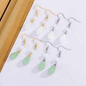 Detailed view of long magnolia petal tassel earrings in white and green jade style