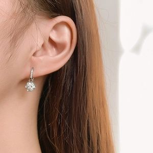 Close-up of a silver-tone drop earring with a round brilliant-cut stone on a model