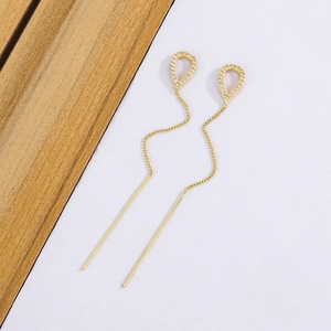 Close-up of gold tassel drop earrings with hollow waterdrop design and micro-pave zircons
