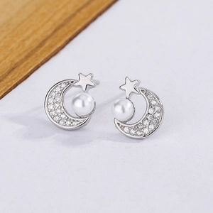 Macro view of star and moon pearl earrings with sparkling zircons and silver finish