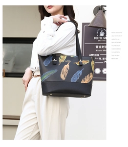 Detail of black tote bag with colorful feather print and silver-tone hardware accents