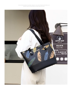 Model view of black feather print tote bag styled in a cafe setting with long shoulder strap