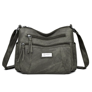 Front view of a sage green multi-pocket crossbody bag with tassel zippers on white background
