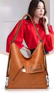 Brown faux leather tote bag detail with zip pockets and rivet flaps shown on a model