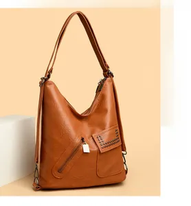 Detail of tan PU leather bag featuring front zipper and decorative rivet pocket