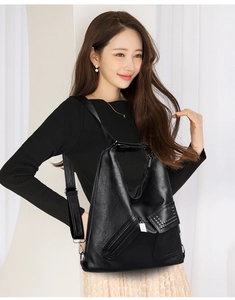 Detail of black faux leather tote bag featuring side pockets with metal rivet studs and zipper