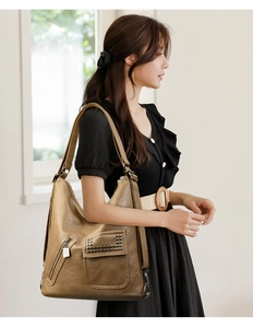 Close-up of retro brown leather tote with rivet accents and practical multi-pocket detail