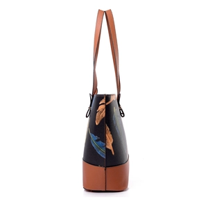 Women's tote bag with feather print and brown leather trim shown from a side profile