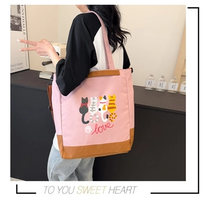 Detail of pink canvas tote bag with cat print, leather trim and adjustable strap