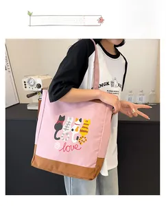 Close-up of a pink canvas tote bag with cartoon cat prints and durable brown bottom detail