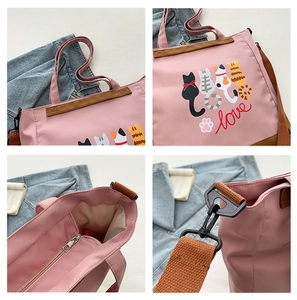 Pink tote bag detail with cartoon cat print, brown straps, and inner zipper pocket