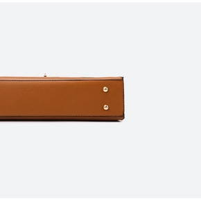 Macro detail of caramel pebbled leather tote bottom with gold protective metal feet