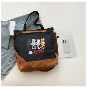 Detail of cartoon cat printed tote bag with leather straps and lifestyle accessories