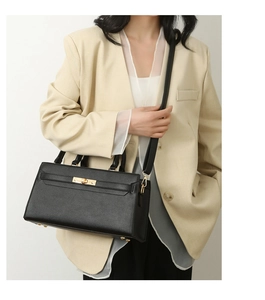 Detail of black pebbled leather tote with golden twist lock and adjustable shoulder strap